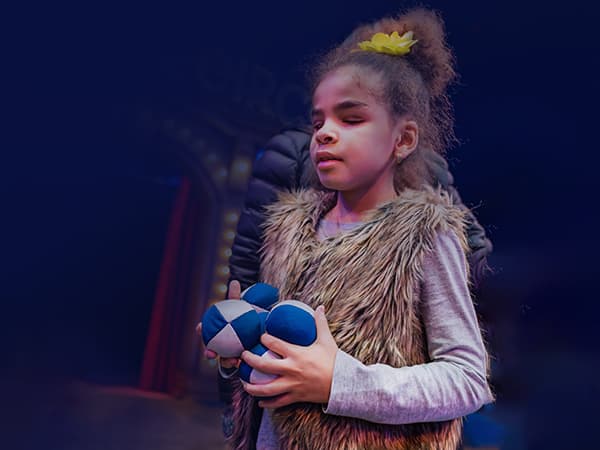 a young blind girl holding juggling balls, smiling
