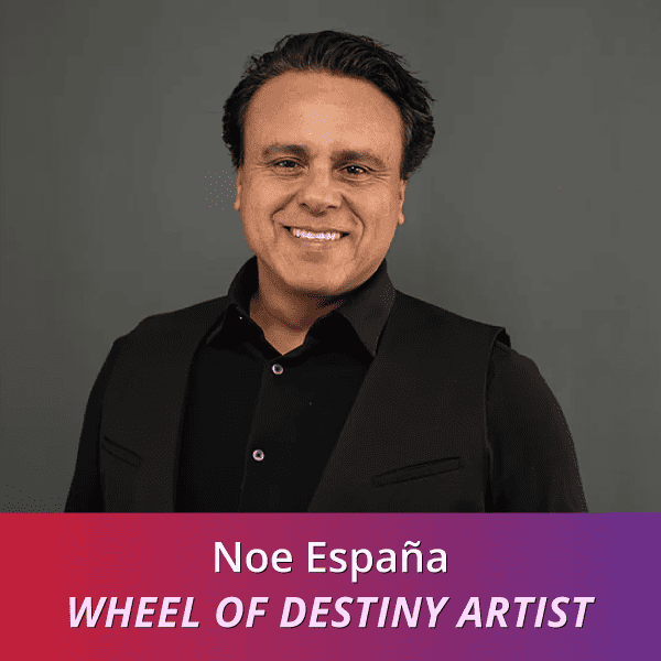 Noe España: Wheel of Destiny Artist, a Hispanic man with short dark hair wearing all black smiling at the camera