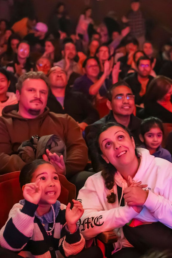 a crowd of people watching omnium circus a little girl and her mother are excitedly looking up