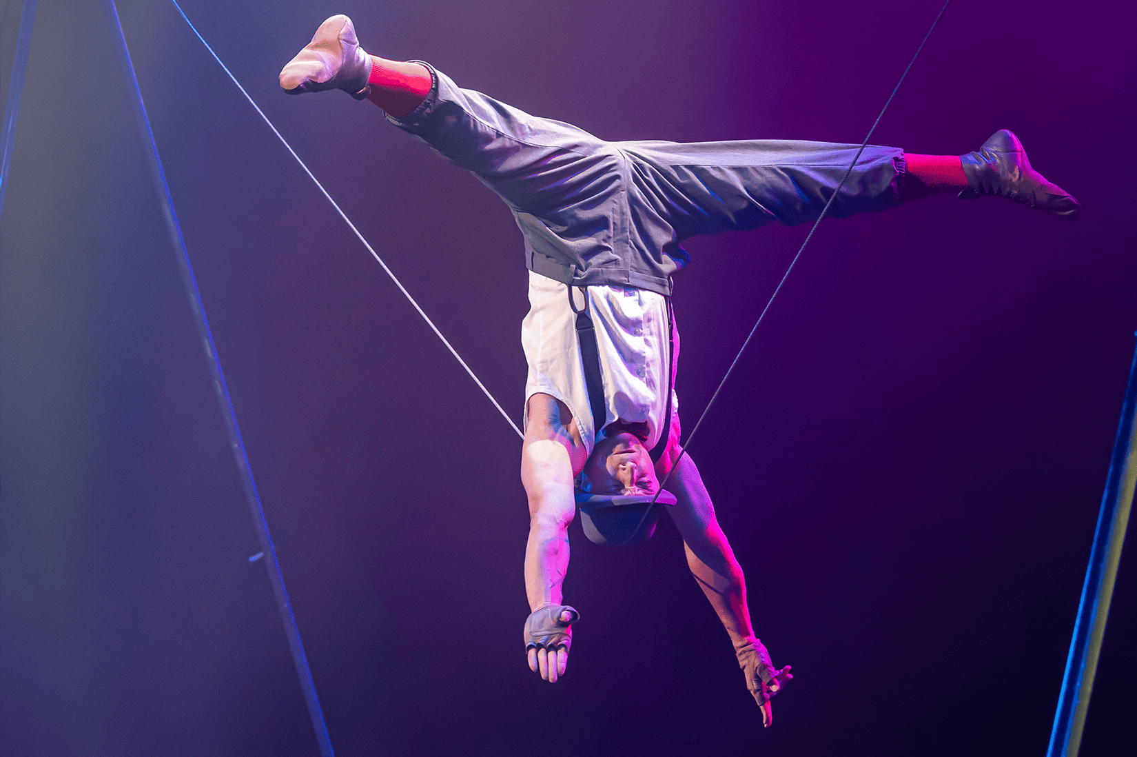 A man balances upside down from a wire.
